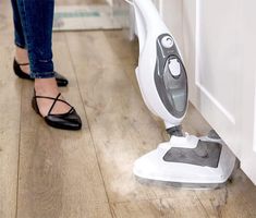 a woman is using a steam mop on the floor