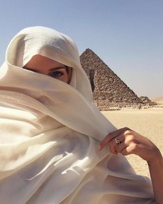 a woman wearing a headscarf in front of the pyramids