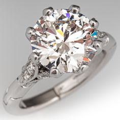 a diamond ring with two diamonds on the side and an accented band around it