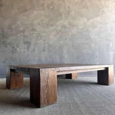 a wooden bench sitting on top of a carpeted floor next to a gray wall