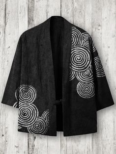 a black and white robe hanging on a wooden wall with an abstract design in the middle