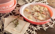 a bowl of soup on a doily next to a cup