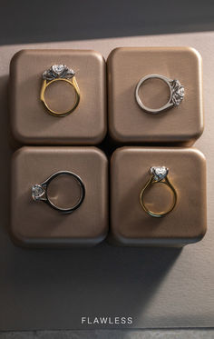 four gold and silver rings sitting on top of each other in front of a wall