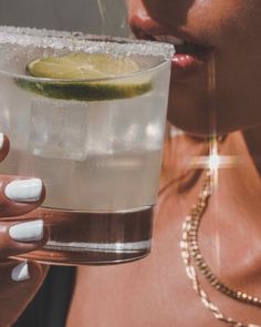 a close up of a person holding a drink with a lime slice on the rim