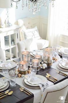 a dining room table is set for christmas with white and gold decorations on the table