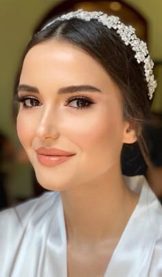 a woman wearing a bridal headpiece with pearls on it's hair and smiling at the camera