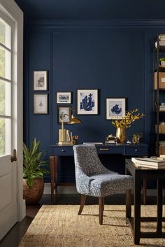 a room with blue walls and pictures on the wall, two chairs in front of a desk