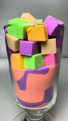 a glass bowl filled with colorful sponges on top of a table