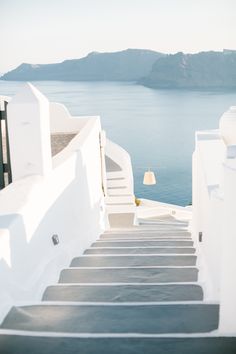 stairs leading up to the top of a building with water and mountains in the background