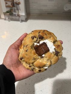 a hand holding a chocolate chip cookie with marshmallows