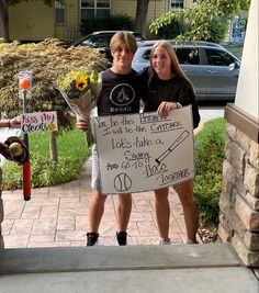 two people standing next to each other holding a sign