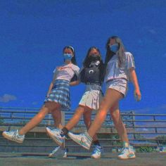 three girls wearing face masks are standing on the side of a bleachers with their arms around each other