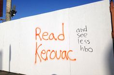 graffiti on the side of a building reads read kerouac and see less hbo