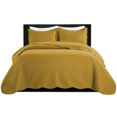 a bed with yellow bedspread and pillows