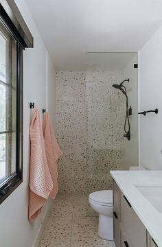 a bathroom with a sink, toilet and shower in it's own area next to a window