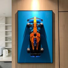 an orange race car is on display in a blue room with wood paneling and white cabinets