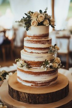 a three tiered wedding cake with flowers on the top is sitting on a wooden stand