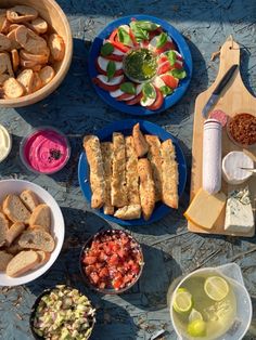 a table topped with plates and bowls filled with food next to breads, salads and condiments