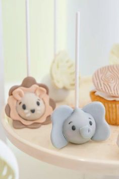 there are cupcakes with animals on them and some candles in the shape of elephants