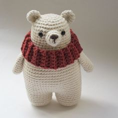 a crocheted teddy bear wearing a red scarf