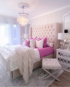 a white and pink bedroom with a chandelier