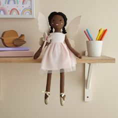 a doll is sitting on a shelf with books and pencils