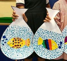 two children holding paper plates with fish on them