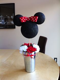 a mickey mouse topiary with flowers in a pail on a table next to a chair