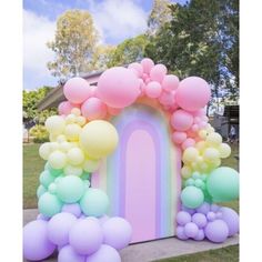 an arch made out of balloons in the shape of a rainbow is on display outside