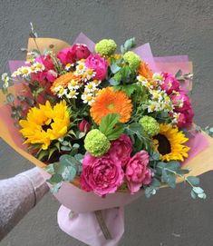 a person holding a bouquet of colorful flowers