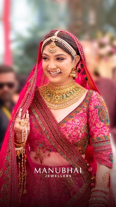 a woman in a red and gold bridal outfit with jewelry on her head, smiling at the camera