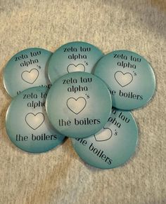 four buttons with the names of different cities and hearts on them, all in blue