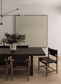 a dining room table with chairs and a vase filled with flowers sitting on top of it