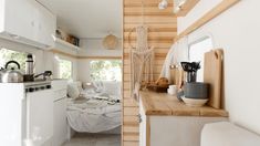 the interior of a tiny home with wood paneling and white furniture, including a kitchenette