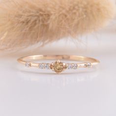 a yellow diamond ring sitting on top of a white table next to a fur ball