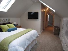 a bed room with a neatly made bed and a flat screen tv on the wall