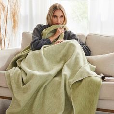 a woman sitting on a couch wrapped in a blanket