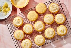 a cooling rack filled with cupcakes and frosting next to bowls of powdered sugar