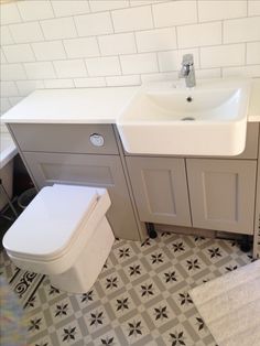 a white toilet sitting next to a sink in a bathroom on top of a tiled floor