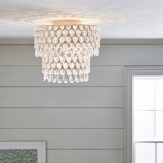 a chandelier hanging from the ceiling in a room with white walls and wood paneling