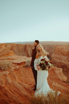 a bride and groom standing in the desert