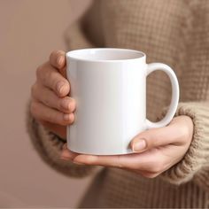 a woman holding a white coffee mug in her hands with both hands on the cup