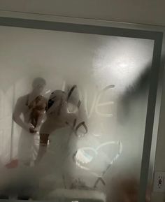 the reflection of two people standing in front of a window with frosted glass on it