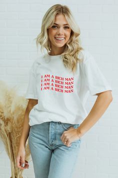 a woman wearing a white t - shirt that says, i am a rich man