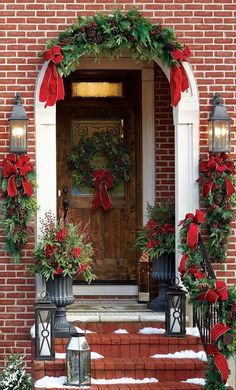 christmas decorations on the front steps of a brick house with wreaths and poinsettias