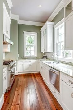 an empty kitchen with wood floors and white cabinets