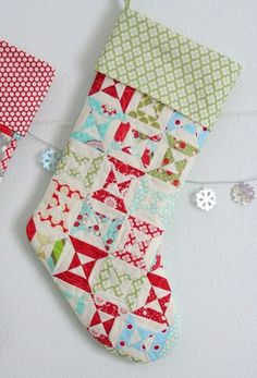 a christmas stocking hanging on a clothesline with some fabric pieces next to it