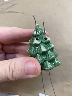 a person is holding a green christmas tree ornament with two needles in it