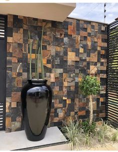 a large black vase sitting on top of a white platform next to a wall covered in tiles