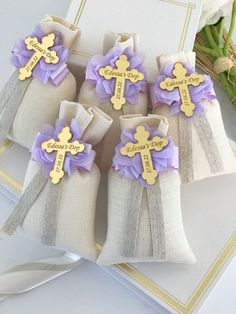 three small bags with wooden crosses on them sitting next to some flowers and a card